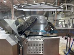 Large industrial meat processing equipment with a conveyor belt revealed in a spacious warehouse—featured in a Meat Processing Equipment Auction from a major meat producer. Metal casing open to showcase the internal mechanisms inside the factory.