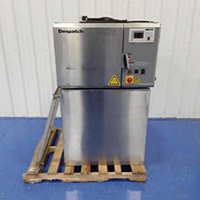 A stainless steel industrial machine, ideal for lab equipment and MRO auction needs, features control buttons and a display labeled Depachi, sitting on a wooden pallet against a blue floor and white paneled wall.