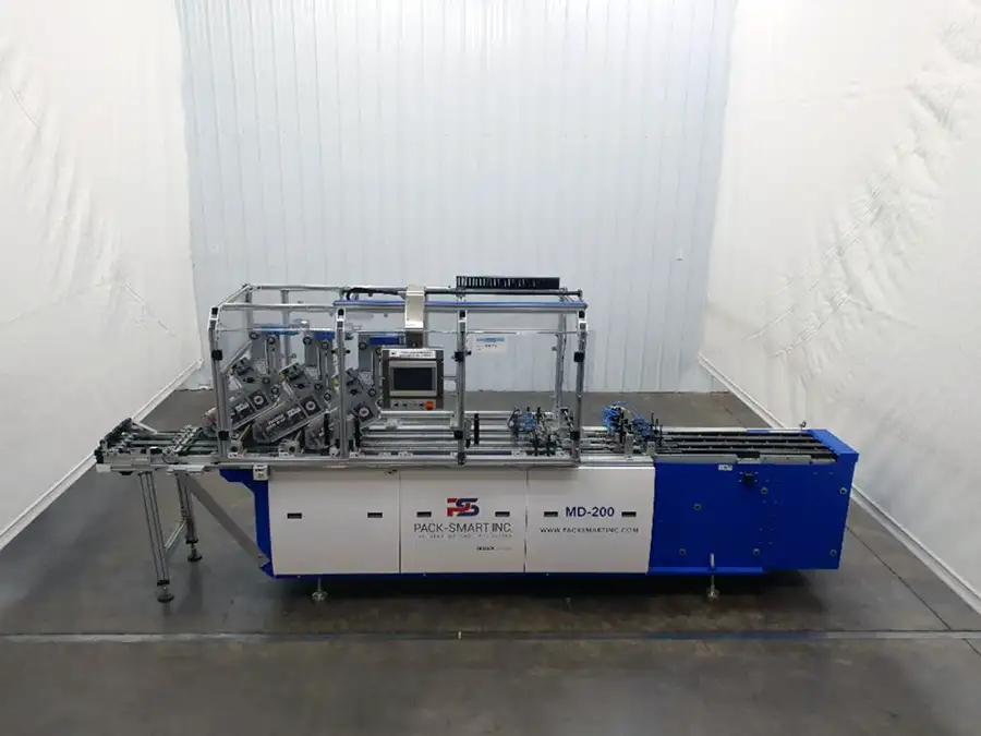 A blue and white industrial packaging machine, labeled Pack-Smart Inc. MD-200, stands in a clean, empty room with white walls and a concrete floor.
