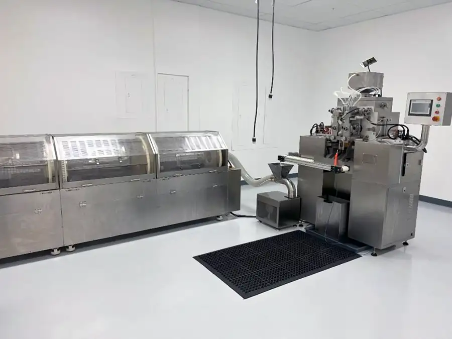 A stainless steel industrial machine from PPT Research: Plant Support Equipment sits in a clean, white-walled room with a glossy floor and overhead wires. A control panel is attached to the right side of the machinery.